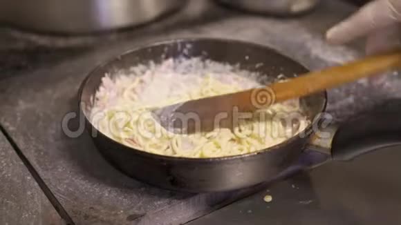 将搅拌好的意大利面条与芝士酱和切碎的培根放入热锅中煎煮视频的预览图