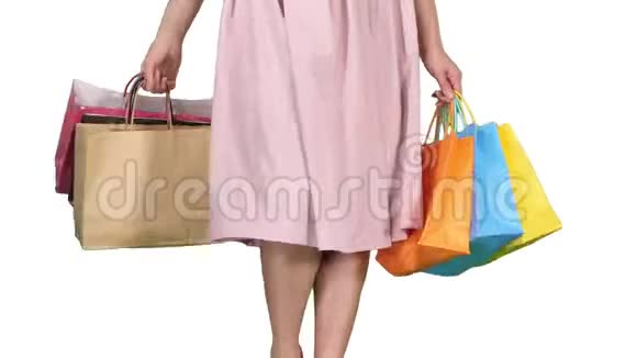 一天后年轻的女人背着购物袋走在白色的背景上视频的预览图