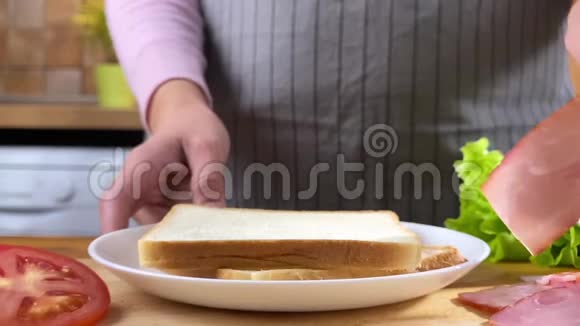 女人在厨房里做三明治配沙拉培根和番茄视频的预览图