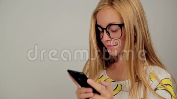 可爱的年轻女子在录音室戴着眼镜在手机上发短信视频的预览图
