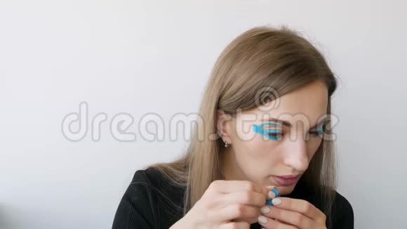 年轻女子在眼睛周围做胶带以恢复活力视频的预览图