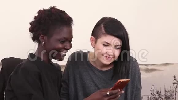 一位非洲裔美国人在她的智能手机上高兴地向她的高加索朋友展示了一些东西视频的预览图