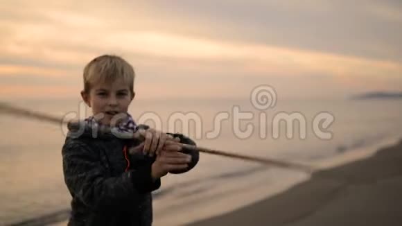那个男孩在日落时站在海滩上把手里的棍子转过来视频的预览图