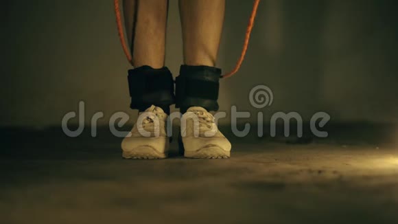 近距离拍摄腿部穿白色运动鞋和黑色脚踝重量做跳绳运动视频的预览图