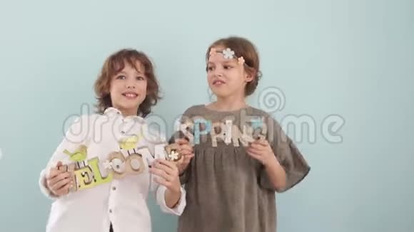 一个男孩和一个女孩跳跳舞并在工作室的蓝色背景和春天装饰在他们的手中一个男孩视频的预览图