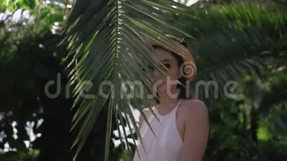 一个有棕榈叶的年轻女子的肖像视频的预览图