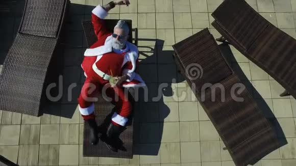 空中观景圣诞老人戴着太阳镜在躺椅上闲逛视频的预览图