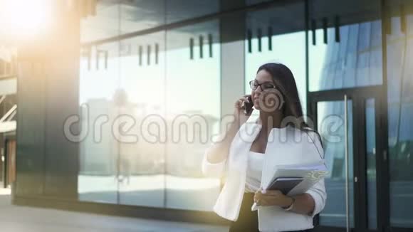 银行家女商人首席执行官在夏天站在建筑背景上打电话视频的预览图