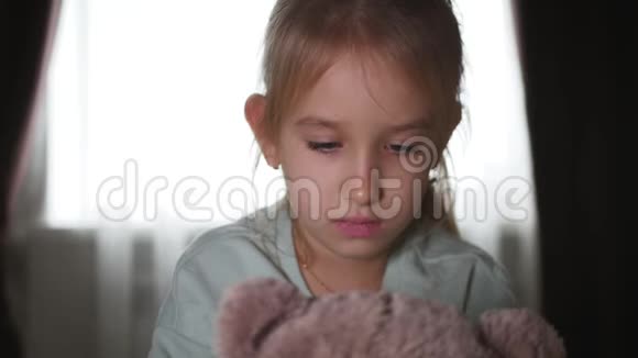 一个悲伤的少女和泰迪熊躺在床上的肖像视频的预览图