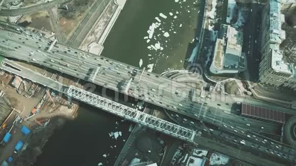 在结冰的河流上沿着桥行驶的汽车的俯视图视频的预览图