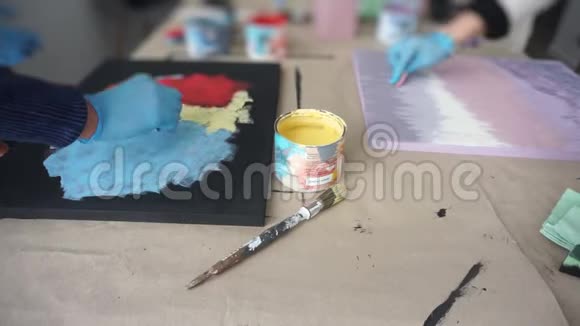艺术家用海绵画一幅抽象的画一罐黄色油漆手套的手艺术工作室视频的预览图