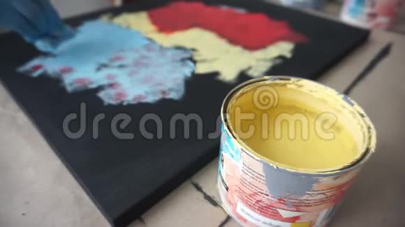 艺术家用海绵画一幅抽象的画一罐黄色油漆手套的手艺术工作室视频的预览图