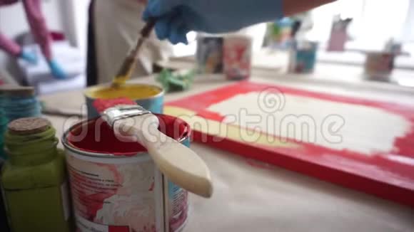 艺术家画了一块木板红色和黄色油漆艺术工作室油漆罐和刷子视频的预览图