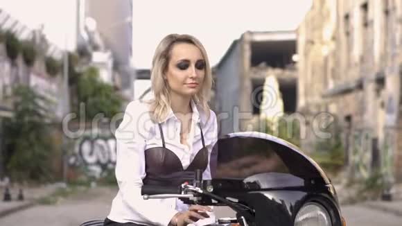 可爱的白种人金发女孩穿着白色衬衫坐在摩托车上英俊的比基尼男人穿着黑色皮夹克视频的预览图