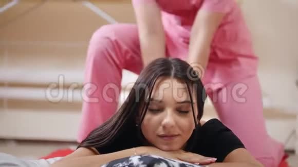 泰式按摩年轻女子躺在垫子上接受按摩享受着视频的预览图