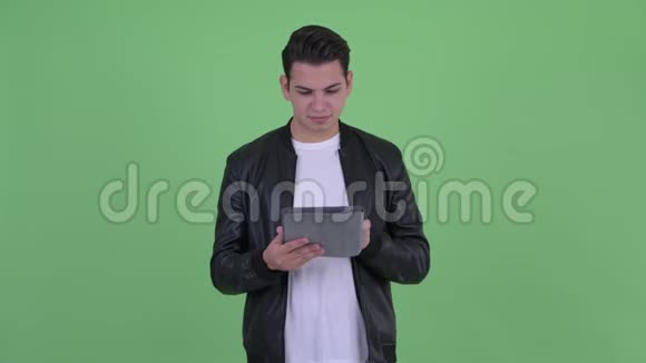 快乐的年轻英俊的多民族人士使用数码平板电脑思考视频的预览图