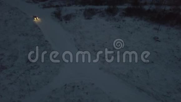 冬季傍晚在城外行驶的白色雪车覆盖的道路上燃放烟花的鸟瞰图视频的预览图