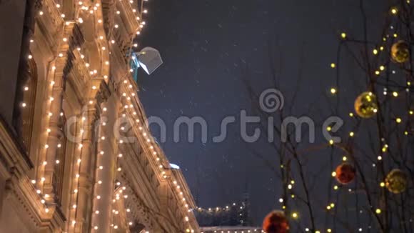 在大雪纷飞的节日夜晚装饰着花环和球在树上的房子视频的预览图