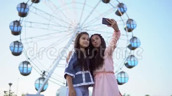 两个漂亮的女朋友在摩天轮的背景下自拍4K视频的预览图