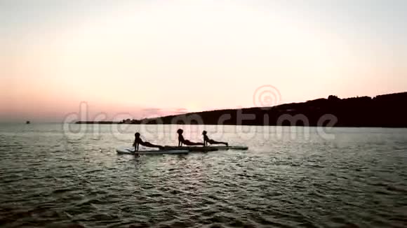 剪影年轻女性在日落时在船上练习瑜伽视频的预览图