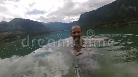 把水溅到摄像机上微笑的人慢动作美丽的山湖视频的预览图