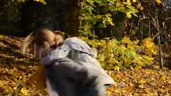 年轻迷人的母亲旋转着把她的小女儿抱在怀里在黄色的落叶中幸福的家庭视频的预览图