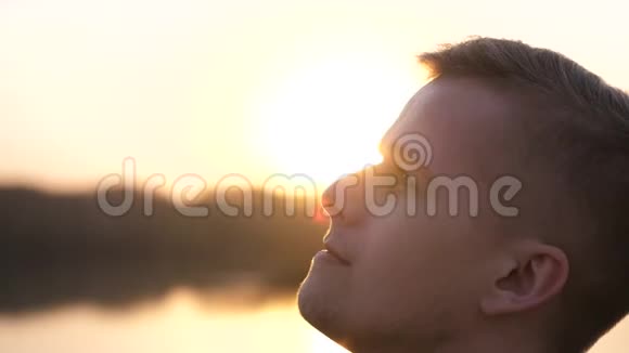 特写一幅忧郁的英俊年轻人的肖像在夕阳下仰望大自然慢动作视频的预览图