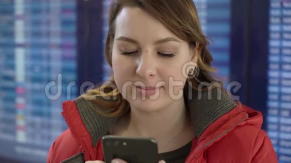 女人拿着手机在机场看信息板视频的预览图