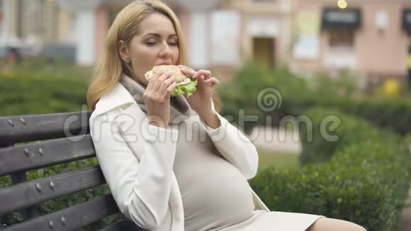 美丽期待的女人吃汉堡坐凳摸肚胃口视频的预览图