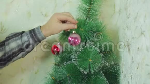 男人手用喜庆的球装饰圣诞树视频的预览图