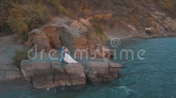 一对新人在海边的山坡上结婚可爱的新郎新娘日落从空中射击视频的预览图