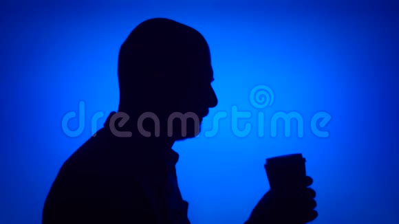 高级男人的剪影用咖啡做蓝色背景男人在侧脸上喝咖啡视频的预览图