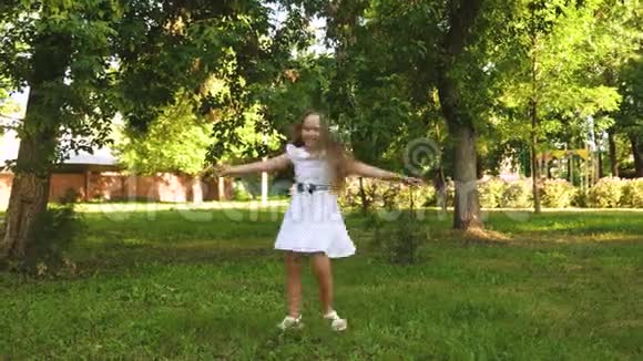 快乐的女孩穿着白色的裙子在夏天的公园里跳舞和旋转视频的预览图