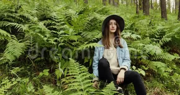 坐在森林里高树的年轻女子视频的预览图