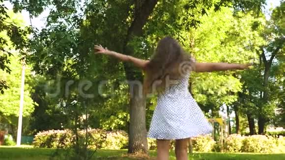 快乐的女孩穿着白色的裙子在夏天的公园里跳舞和旋转视频的预览图