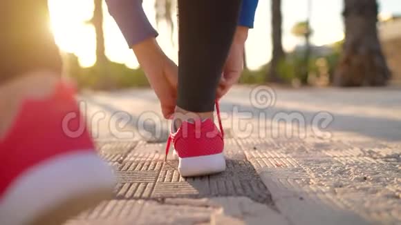 在日落时分女人系鞋带沿着棕榈大道奔跑后景以不同的速度拍摄视频的预览图