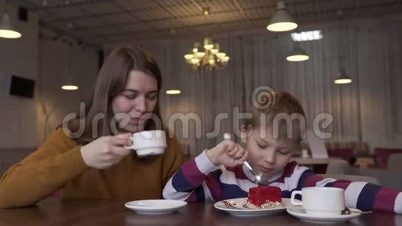 可爱的年轻母亲喝着浓缩咖啡和她可爱的儿子交谈视频的预览图