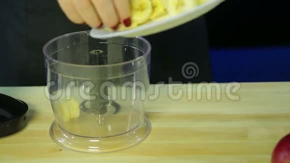 女人把一根香蕉放进搅拌机的碗里视频的预览图