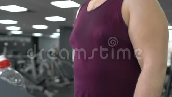 胖乎乎的男人在跑道上行走在健身房跑步机上热身视频的预览图