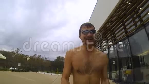 男人朝游泳池跑去手里拿着相机在自己面前跳跃视频的预览图
