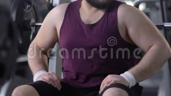 不自信的超重男性在健身房看他的胖肚子减肥节食视频的预览图