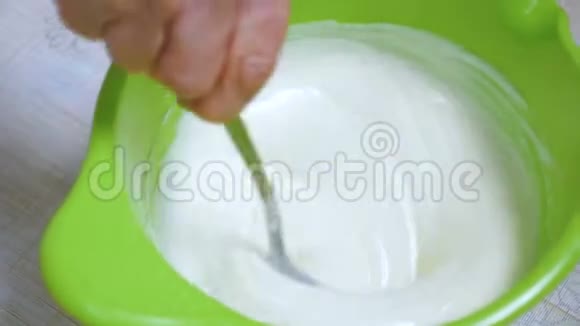 家庭主妇用勺子混合酸奶油蛋糕视频的预览图