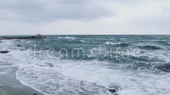 在寒冷的一天海滩上的海浪在暴风雨中戏剧性地看到了敖德萨海岸附近被洪水淹没的船慢动作视频的预览图