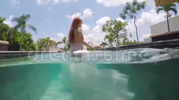 新娘穿着婚纱在一个热带别墅的游泳池里水下视频的预览图