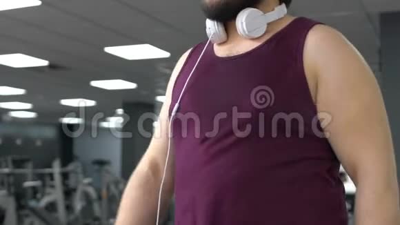 鼓舞人心的胖子戴着耳机在健身房跑步耐力健康视频的预览图