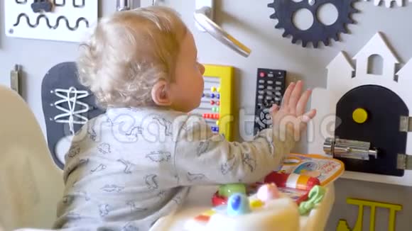 可爱的小男孩在墙上玩忙碌的木板为孩子们准备的繁忙的棋盘木制游戏桌视频的预览图