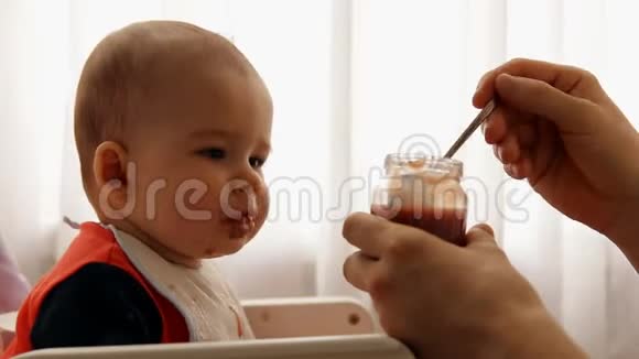 年轻快乐的父亲喂养他的儿子婴儿水果泥视频的预览图