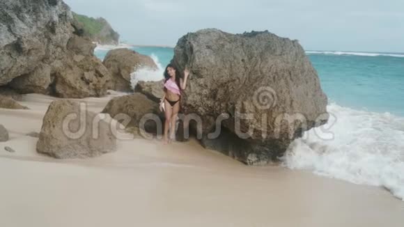 慢镜头穿着泳装在沙滩上摆姿势的美丽性感女孩的肖像背景是波浪拍摄的是Stealam视频的预览图