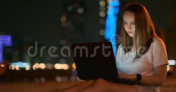 年轻的女设计师晚上在棕榈树下的笔记本电脑上远程工作视频的预览图