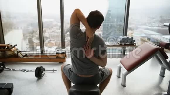 运动的男人在健身前伸展手臂健身年轻男性运动员站在酒店健身房室内视野开阔视频的预览图